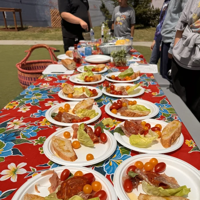 plates of food on a long table covered with a red floral tablecloth